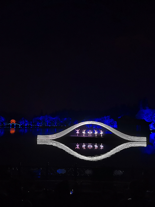 A vibrant performance or show taking place on or near West Lake in Hangzhou.