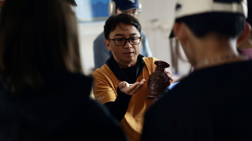 School trip leader showing students a historical artifact